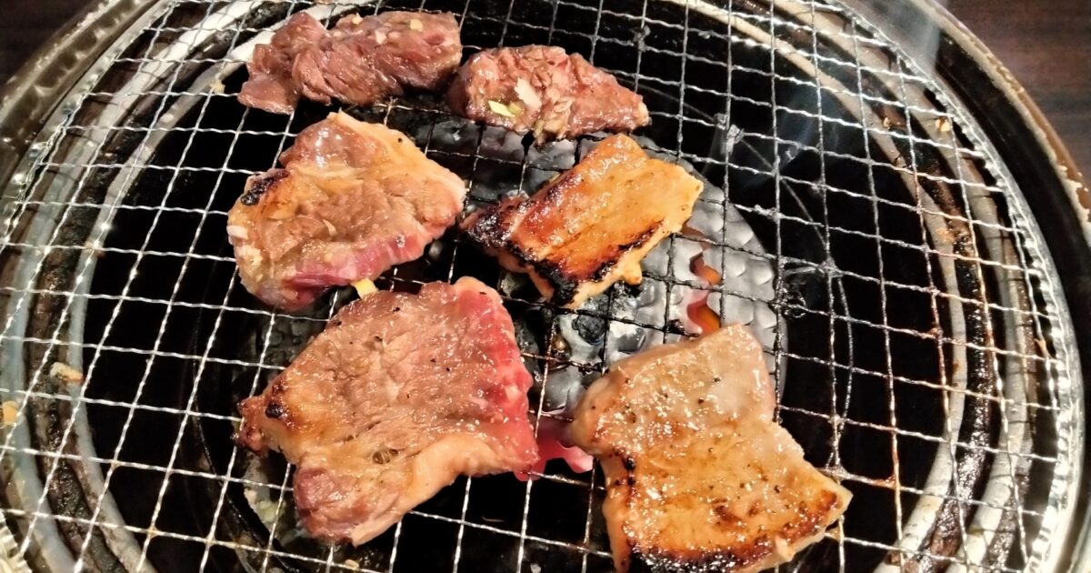 炭火焼き網で焼かれる焼肉盛り合わせ