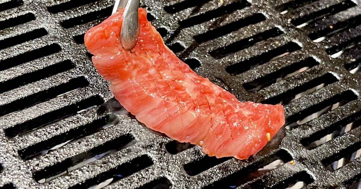 トングで焼かれる赤身焼肉の一枚