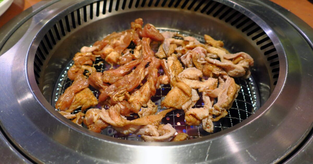 網で焼かれる味付け鶏肉の焼肉プレート