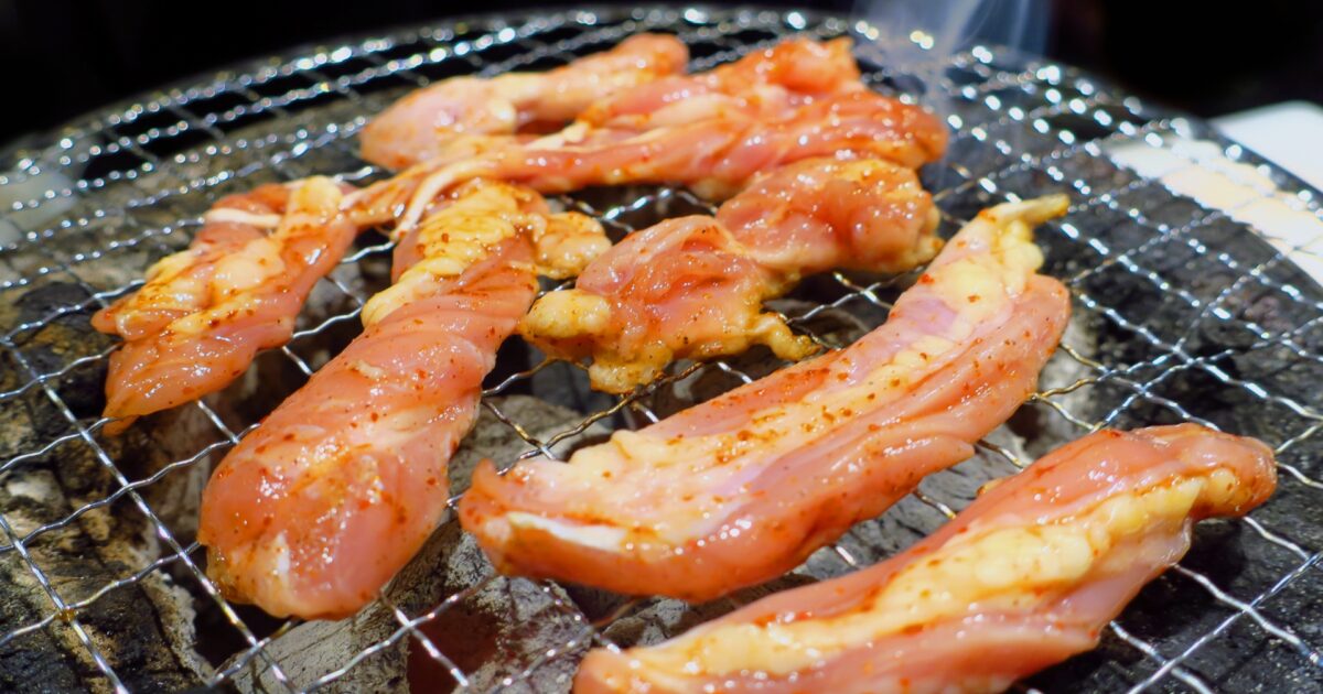 炭火で焼かれるタレ漬け鶏せせりの焼肉シーン