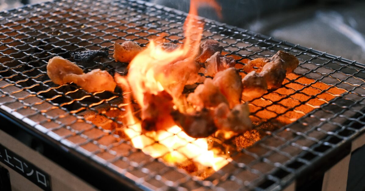 炭火で炎を上げながら焼かれる鶏肉のバーベキュー
