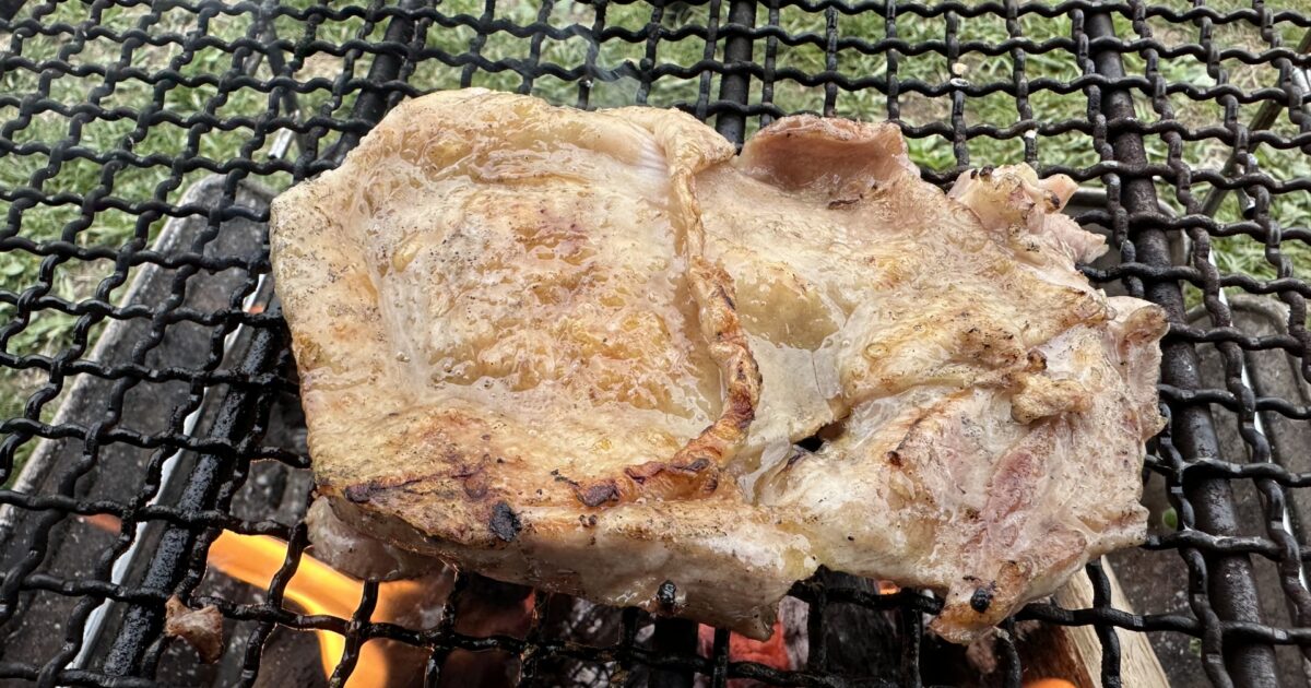 炭火で豪快に焼かれる骨付き鶏もも肉のバーベキュー