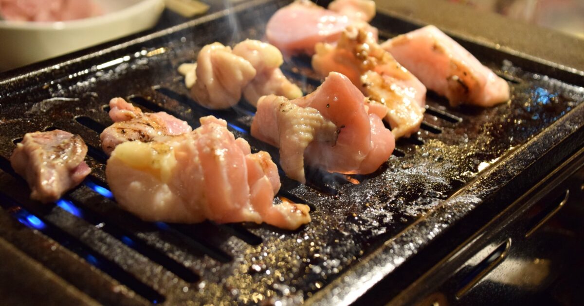 ガスコンロで焼かれる鶏もも肉の焼肉シーン