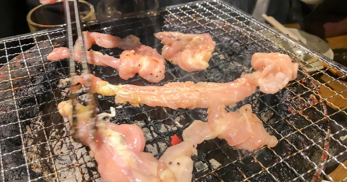 炭火で焼かれる鶏せせりをトングで裏返す様子