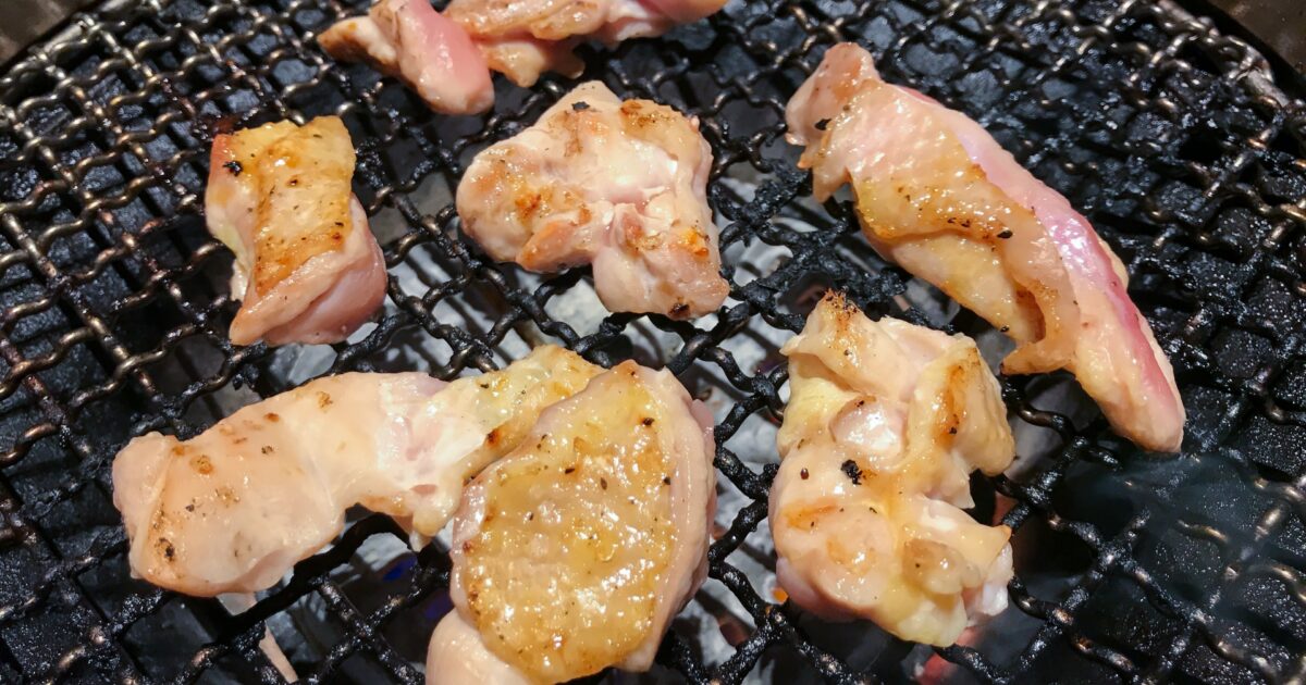 炭火網で焼かれる一口サイズの鶏もも肉