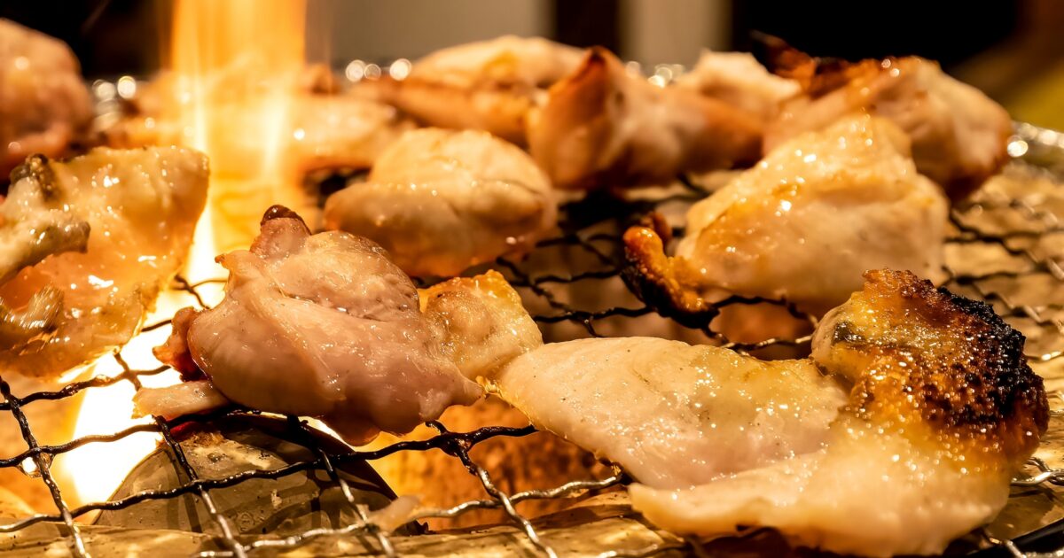 脂が滴る鶏肉を炭火で香ばしく焼く焼肉シーン