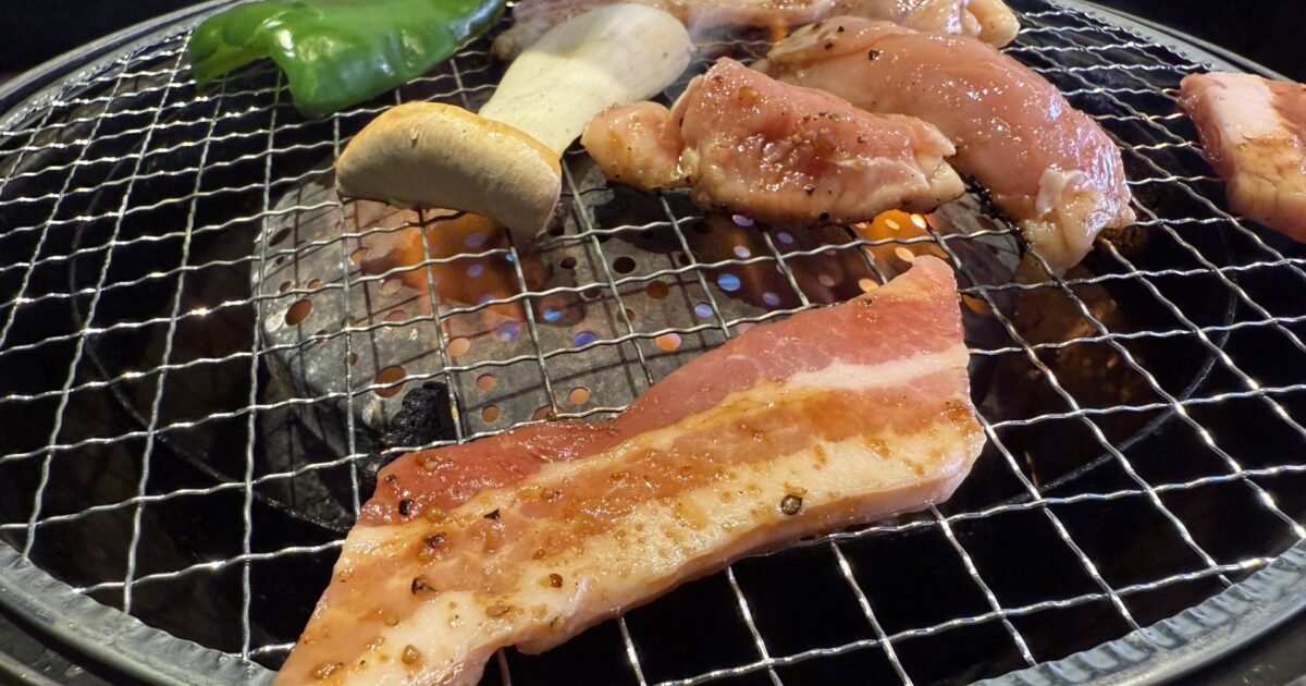 網焼きで調理中の豚バラ肉と野菜の焼肉プレート