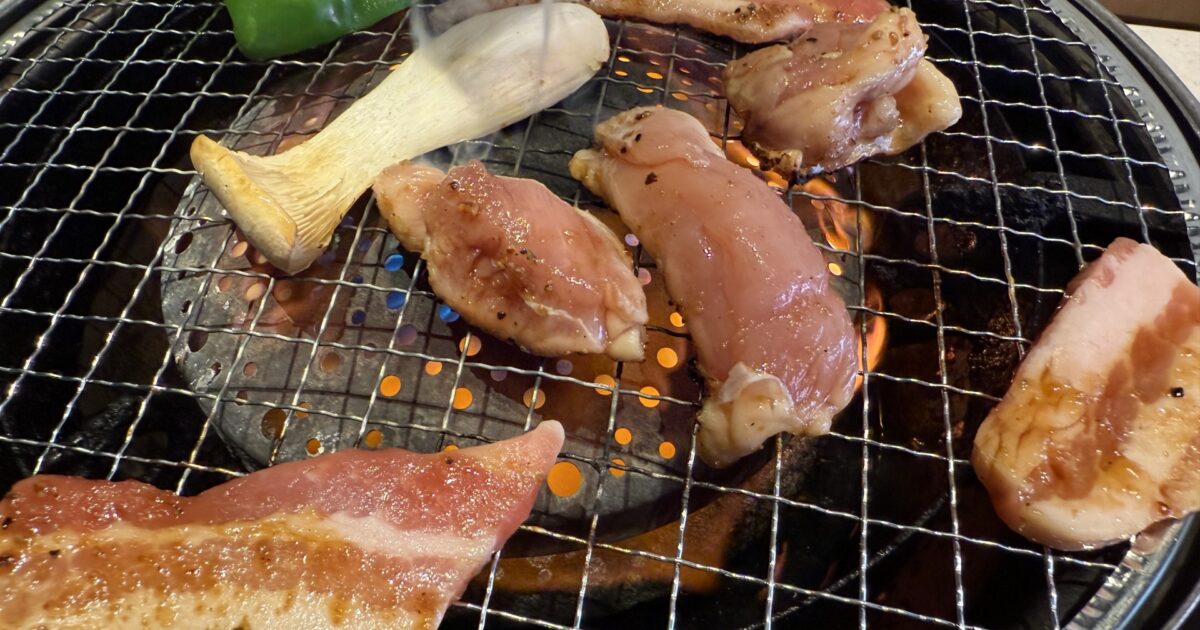 炭火で焼かれる豚バラ肉と鶏肉と野菜の盛り合わせ