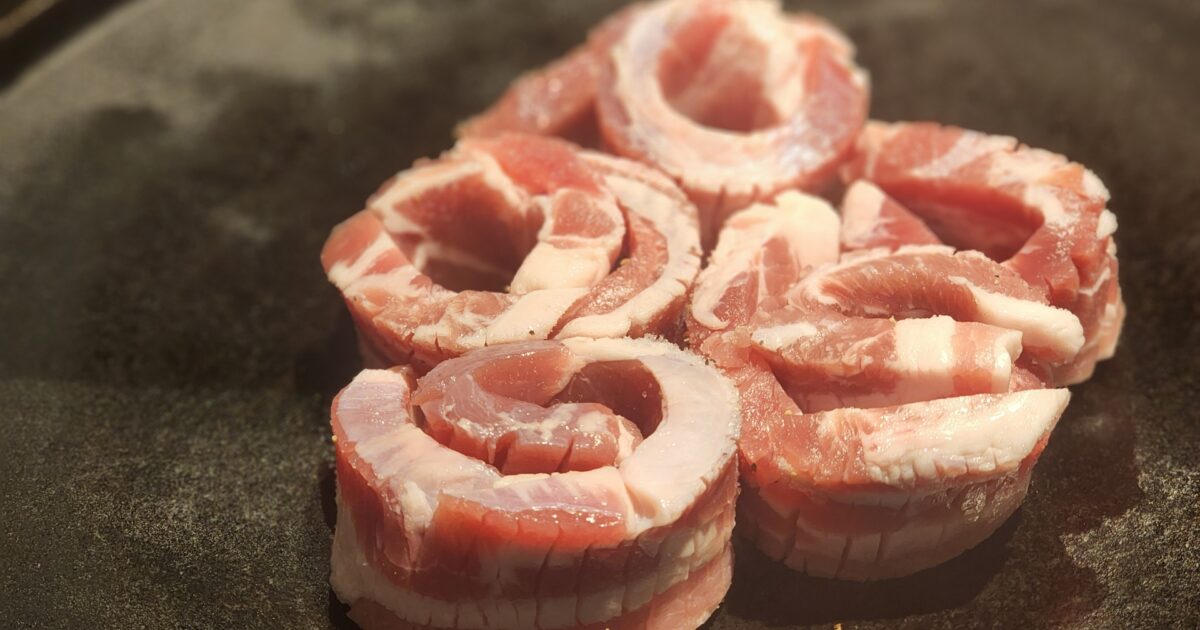 丸めた厚切り豚バラ肉を鉄板で焼くサムギョプサル
