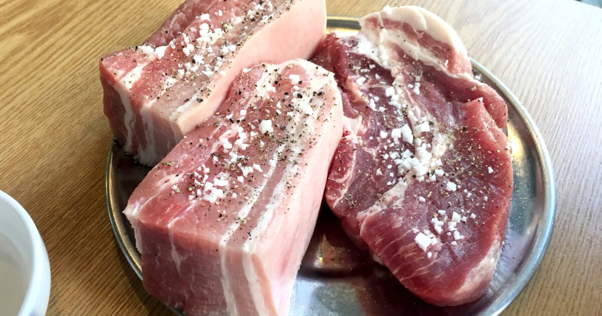 粗塩と胡椒がかかった厚切り豚肉の焼肉用プレート