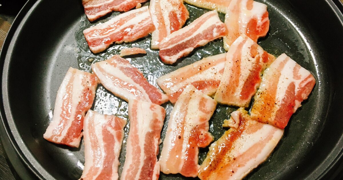 ホットプレートで焼かれる豚バラ肉の焼肉盛り合わせ