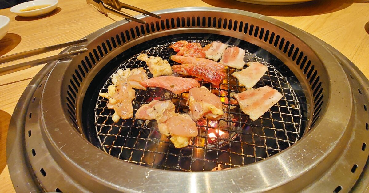 炭火で焼かれる豚肉と鶏肉の焼肉盛り合わせ