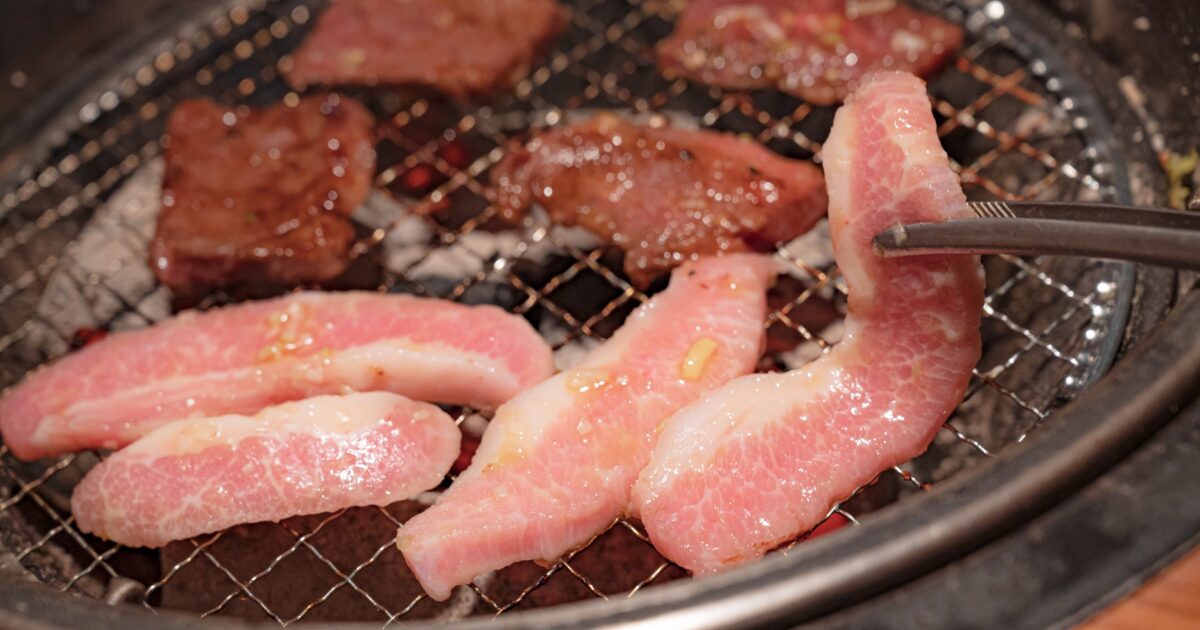 網で焼かれる厚切り豚バラ肉と牛カルビ