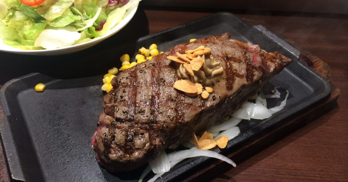 ガーリックバターをのせた鉄板ステーキとサラダ
