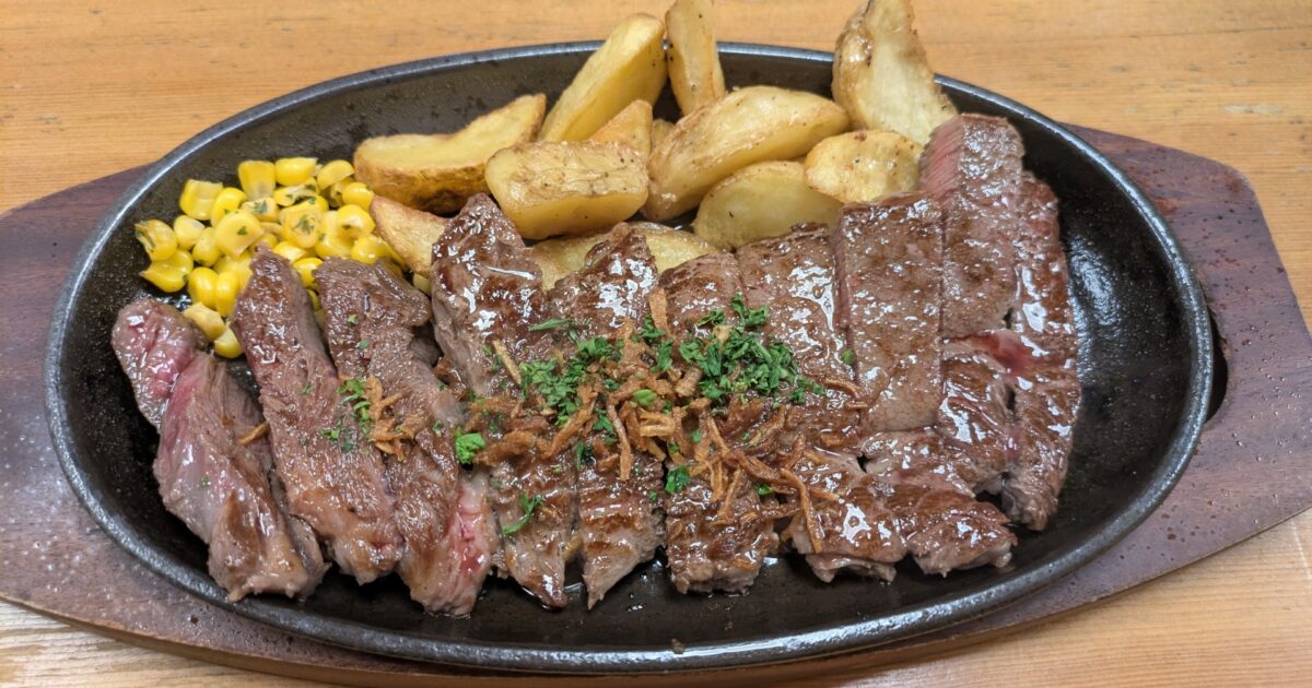 鉄板で焼かれたカットステーキとポテトコーン添え