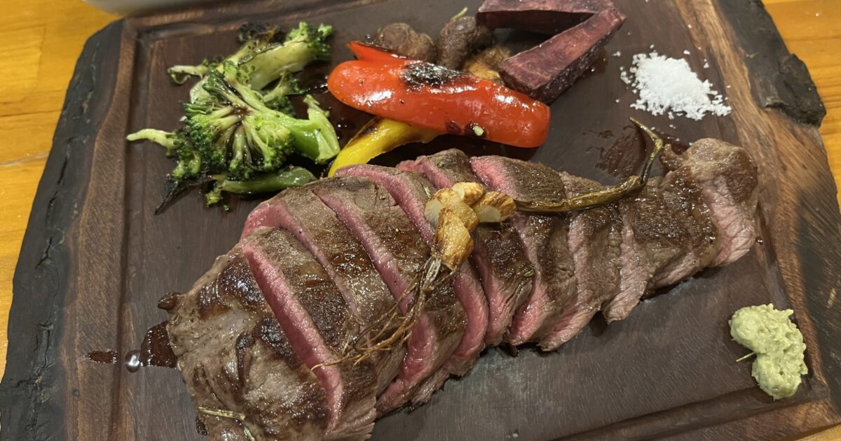 木製プレートに盛られた厚切りステーキと焼き野菜