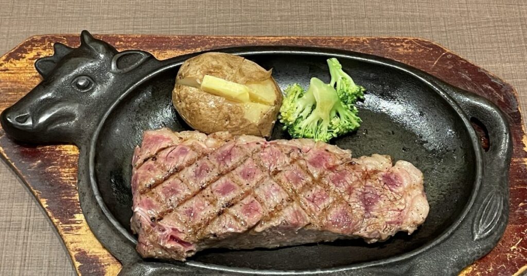 鉄板に乗せたステーキとベイクドポテトとブロッコリー